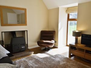 a living room with a fireplace and a chair and a mirror at Shenval Cottage - 28280 in Glenlivet