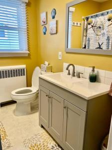 ein Badezimmer mit einem WC, einem Waschbecken und einem Spiegel in der Unterkunft Seacret Hideaway in Point Pleasant Beach