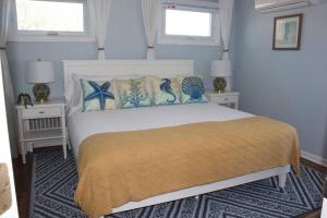 ein Schlafzimmer mit einem Bett mit zwei Tischen und zwei Fenstern in der Unterkunft Seacret Hideaway in Point Pleasant Beach