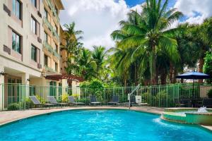 una piscina di fronte a un edificio con palme di Courtyard Fort Lauderdale SW Miramar a Miramar