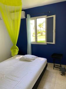Cet appartement comprend une chambre dotée d'un lit avec un mur bleu et une fenêtre. dans l'établissement Lullaby of the sea Crystal beach Saint François, à Saint-François