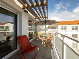 a balcony with a table and chairs and an umbrella at Appartement neuf PMR, 3 pièces, centre de Saint-Pierre, 4 couchages, jardin, balcon, 3 étoiles - FR-1-246A-245 in Saint-Pierre-dʼOléron