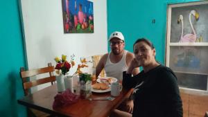 Dois homens sentados numa mesa com um prato de comida. em Puerto Ayora Island em Puerto Ayora