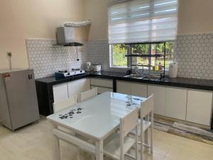 a kitchen with a white table and white chairs at King's Cottage Homestay Kubang Kerian in Kota Bharu