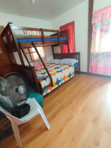 a bedroom with bunk beds and a chair with a fan at Puerto Galera Transient Kubo Guest Place in Puerto Galera