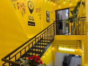 a yellow building with a staircase with flowers and lights at Ga Homestay in Hai Phong