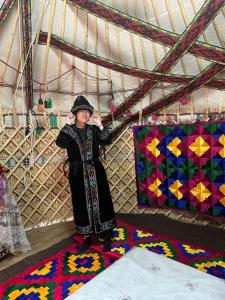 a woman is standing in a tent with a quilt at Guest house "NIKA", Nukus in Nukus