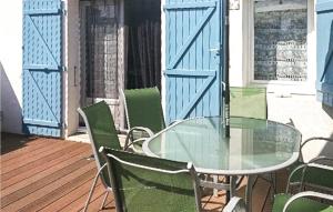 a glass table and chairs on a porch with blue doors at Stunning Home In La Faute Sur Mer in La Faute-sur-Mer