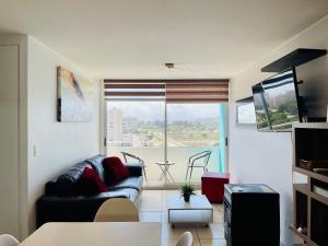sala de estar con sofá y ventana grande en Nicoland Playa y piscina La Serena, en La Serena