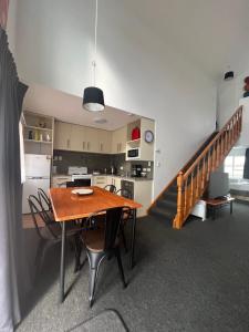 a kitchen and dining room with a table and a staircase at ASURE Green Gables Motel in Lower Hutt