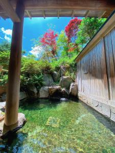 a pond in a garden with a waterfall at Hakuunsou in Takayama