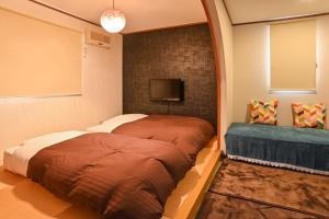 a bedroom with a bed and a tv on a wall at Lake side inn Beehive in Kitashiobara