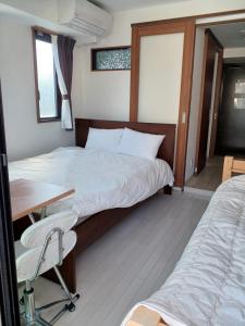 sypialnia z 2 łóżkami, biurkiem i stołem w obiekcie オリエントシティ南堀江Ⅱ w Osace