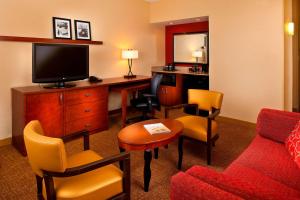 a hotel room with a desk with a tv and chairs at Courtyard Melbourne West in Melbourne