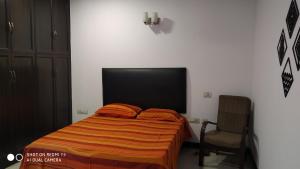 Blessings Noida Home stay في نويدا: غرفة نوم بسرير وبطانية برتقالية وكرسي