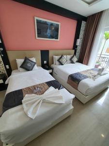 2 Betten in einem Zimmer mit rosa Wänden in der Unterkunft Muine Sports Hotel in Mui Ne