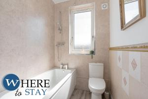 baño con bañera, aseo y ventana en Apartment beyond forth Bridges - 3bed free parking, en Inverkeithing