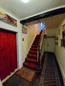 a hallway with a staircase with a red curtain at Historic Apartment in Oatlands