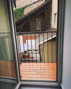 eine offene Tür zu einem Balkon mit einer Holzterrasse in der Unterkunft Appartement Centrale Confort in Montalieu-Vercieu