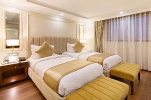 a hotel room with two beds and a mirror at Hotel Shanker-Palatial Heritage Kathmandu in Kathmandu