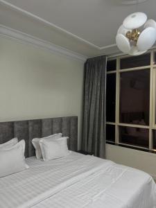 a bedroom with a bed with white sheets and a window at بيوتي روز لشقق المخدومه in Abha