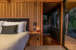 1 dormitorio con 1 cama y pared de madera en The Enchanted Retreat - Unforgettable Luxury Glamping, en Havelock North