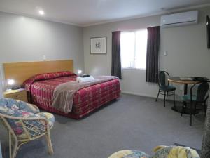 Habitación de hotel con cama, mesa y sillas en Commodore Court Motel en Blenheim