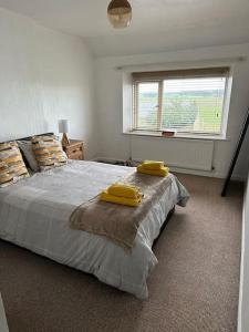 um quarto com uma cama grande e 2 almofadas amarelas em Hare view Cottage - Northumberland 