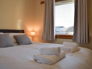 a bedroom with a white bed with towels on it at The Hoolit in Crieff