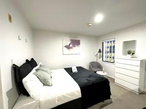 ein Schlafzimmer mit einem schwarzen und weißen Bett und einer Kommode in der Unterkunft Cozy 1-bedroom unit at CBD in Auckland