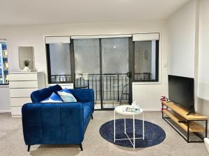 een woonkamer met een blauwe bank en een tv bij Cozy 1-bedroom unit at CBD in Auckland