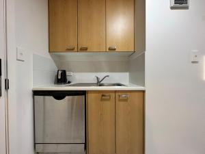 een keuken met houten kasten en een wastafel bij Cozy 1-bedroom unit at CBD in Auckland