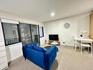 een woonkamer met een blauwe bank en een tafel bij Cozy 1-bedroom unit at CBD in Auckland