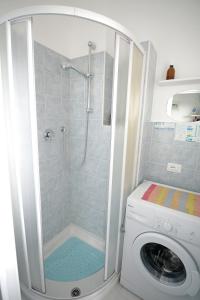 a bathroom with a shower and a washing machine at Donatella Mini Apartment in Marotta