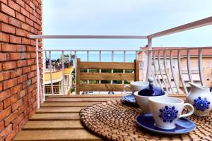 een tafel met kopjes en schotels op een balkon bij Vento di Mare in Piraino