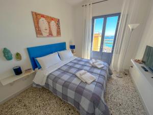 a bedroom with a bed with a blue headboard and a window at La casa del pescatore in Sciacca