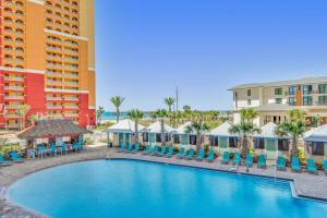 パナマ・シティ・ビーチにあるCalypso 3-205の青い椅子と建物が備わるリゾートのプールを利用できます。