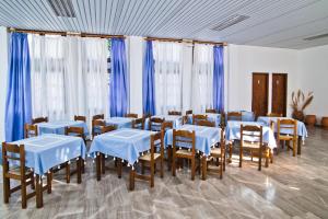Cette chambre comprend des tables, des chaises et des rideaux bleus. dans l'établissement Pegasus, à Massouri