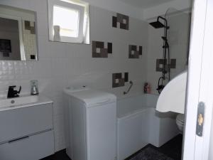 uma casa de banho branca com uma banheira e um lavatório em Gemini Vendégház em Harkány