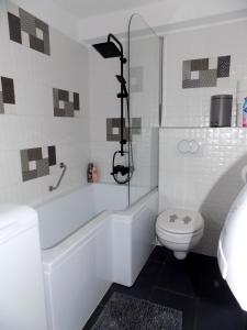 a white bathroom with a toilet and a bath tub at Gemini Vendégház in Harkány