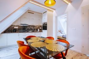 a dining room with a glass table and orange chairs at Apartamenty Księżycowe SPA Wenus i Mars in Zakopane