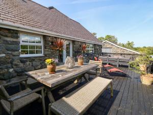 een houten tafel en banken op een terras bij Bodrual Cottage in Caernarfon