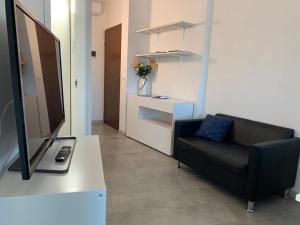 a living room with a black couch and a television at PeschieraView Flat x4 in Peschiera del Garda