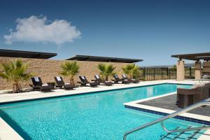 a swimming pool with lounge chairs next to a building at SpringHill Suites by Marriott Milpitas Silicon Valley in Milpitas
