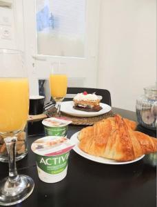 a table with two plates of bread and orange juice at Le Cocon de Poissy in Poissy