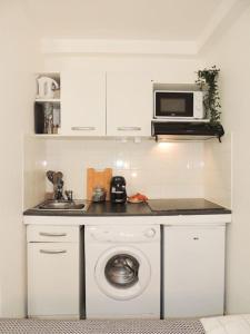 a kitchen with a washing machine and a microwave at Le Cocon de Poissy in Poissy