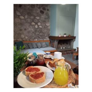 a table with two plates of bread and orange juice at Potamolithos Suites 2 in Konitsa