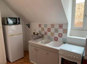 a small kitchen with a sink and a refrigerator at Charmante petite maison d’hôte, centre ville AUTUN in Autun