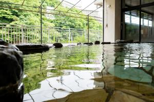 a swimming pool in a building with water on the floor at Monogusa no Yado Hanasenkyo in Nikko