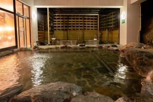 a pool of water in a room with rocks at Monogusa no Yado Hanasenkyo in Nikko
